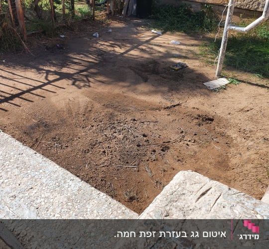אזור אדמה עם גדר מתכת וחפצים שונים